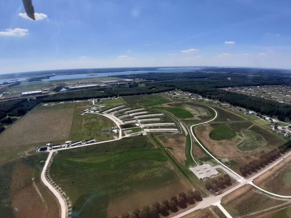 Een luchtfoto van het Eemged in aanbouw. Te zien zijn wegen de wegen en de karakteristieke gebogen vorm van de Eemgoed longhouses. Op de acthergrond is een heldere lucht met enkele wolken.