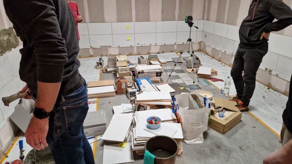 De Eemhuis keuken in aanbouw met verschillende soorten tegels, gereedschap en materialen verspreid over de vloer.