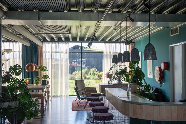 Het interieur van het Eemhuis met een bar, planten en grote ramen die uitzicht bieden op een tuin. De ruimte is licht en uitnodigend